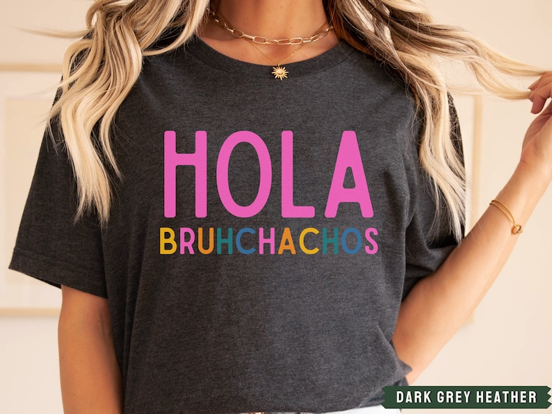 May include: Dark grey heather t-shirt with the text "HOLA BRUHCHACHOS" in pink, yellow, blue, green, and orange.