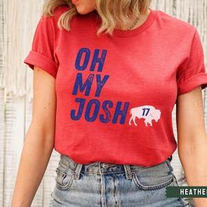 May include: Heather red t-shirt with the text "Oh My Josh" in blue and a white buffalo with the number "17" on it.