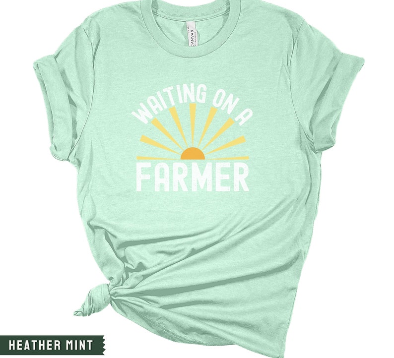 Może przedstawiać: Jasnozielony t-shirt z napisem "Waiting on a Farmer" białymi literami. Nad tekstem znajduje się ż&oacute;łte słońce z promieniami.