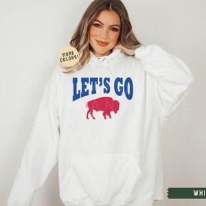 May include: White hooded sweatshirt with the text "Let's Go" in blue and a red buffalo silhouette.