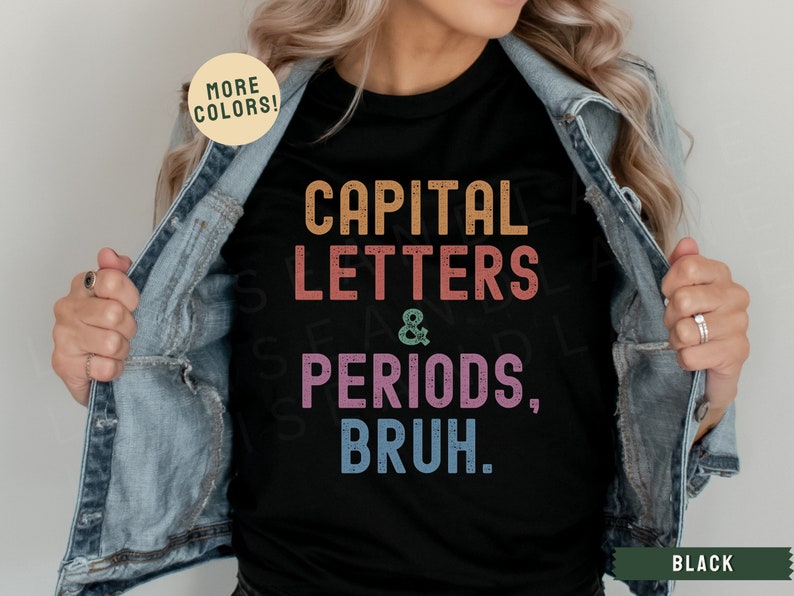 Puede incluir: Una camiseta negra con un gr&aacute;fico de estilo vintage que dice "CAPITAL LETTERS & PERIODS, BRUH." El gr&aacute;fico est&aacute; en colores arco&iacute;ris. La camiseta est&aacute; siendo modelada por una persona que lleva una chaqueta vaquera.