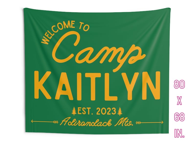 May include: A green and gold welcome to camp sign with the name Kaitlyn and the text "EST. 2023 Adirondack Mts." The sign is 80 inches by 68 inches.