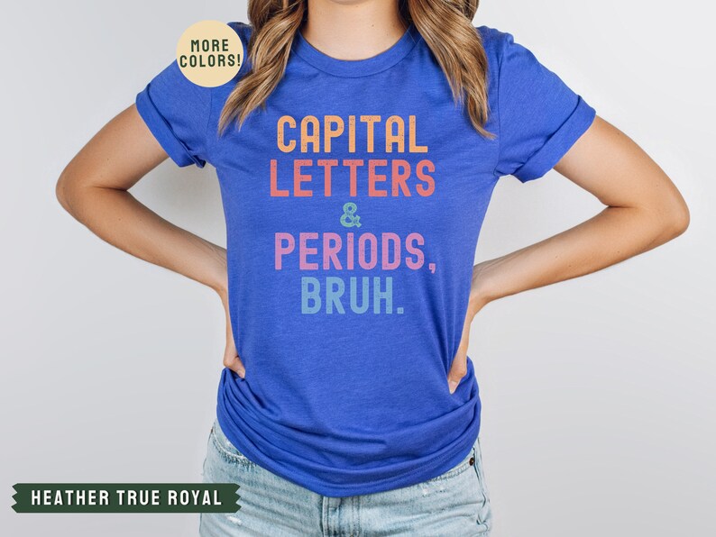 Puede incluir: Una camiseta azul real con el texto "CAPITAL LETTERS & PERIODS, BRUH." en colores arco&iacute;ris.