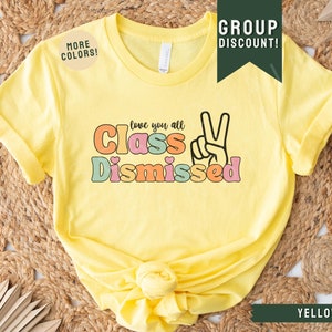 May include: Yellow t-shirt with the text "Love you all Class Dismissed" in colorful letters with a peace sign.