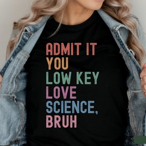 May include: Black t-shirt with the text "ADMIT IT YOU LOW KEY LOVE SCIENCE, BRUH" in rainbow colors.