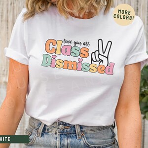 May include: White t-shirt with a colorful graphic that says "Love you all Class Dismissed" with a peace sign.