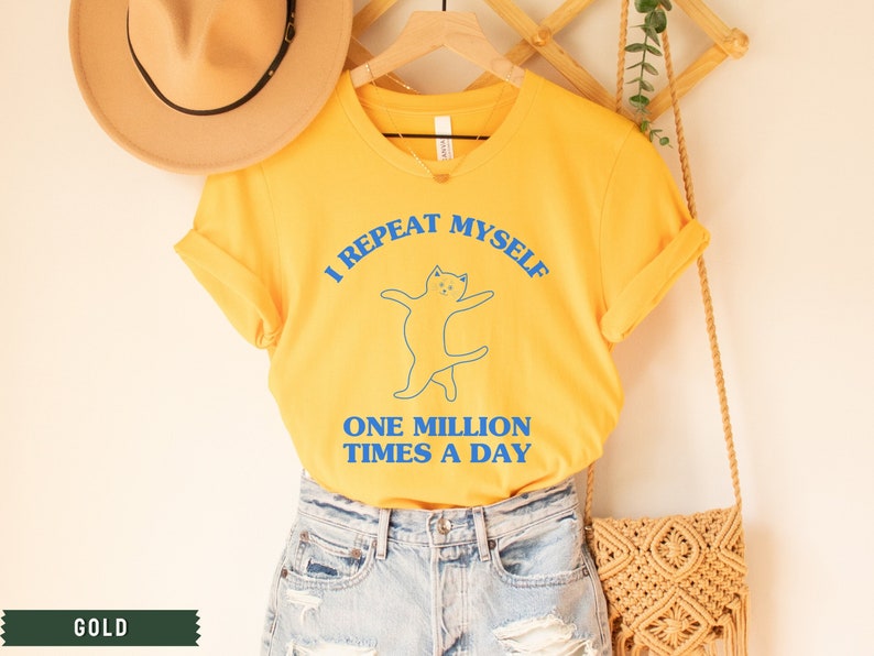 May include: Yellow t-shirt with a blue cat graphic and the text "I repeat myself one million times a day".