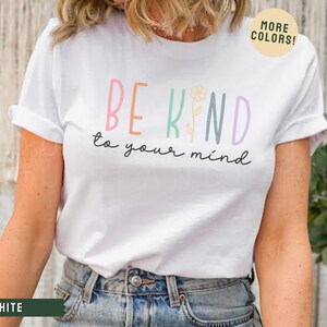 May include: White t-shirt with a colorful graphic that says "Be Kind to your mind" with a flower illustration.