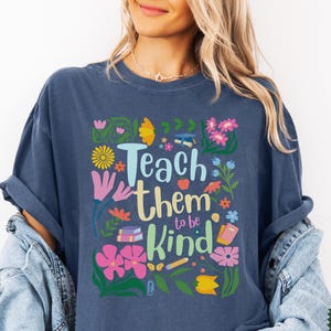 May include: A navy blue t-shirt with a floral design and the text "Teach them to be kind".