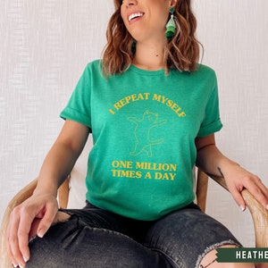 May include: A green t-shirt with a yellow graphic of a cat and the text "I repeat myself one million times a day".