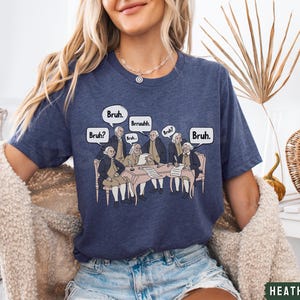 Peut inclure: Un t-shirt bleu marine avec un graphique de p&egrave;res fondateurs assis autour d'une table avec des bulles de dialogue qui disent "Bruh."  "Bruh?"  "Bruh."  "Brrruuhh."  "Bruh."