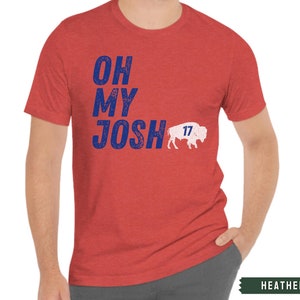 May include: A heather red t-shirt with a blue and white distressed graphic that says "Oh My Josh" with a white buffalo silhouette and the number "17" on it.