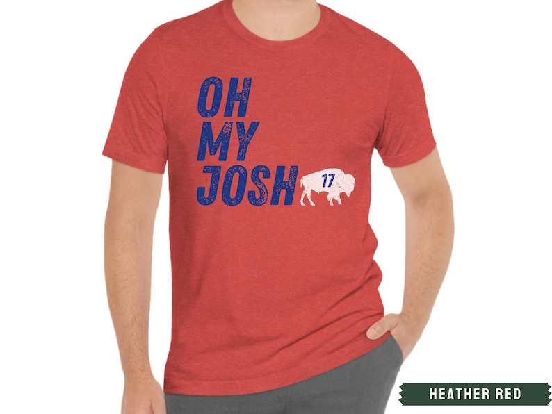 May include: A heather red t-shirt with a blue and white distressed graphic that says "Oh My Josh" with a white buffalo silhouette and the number "17" on it.