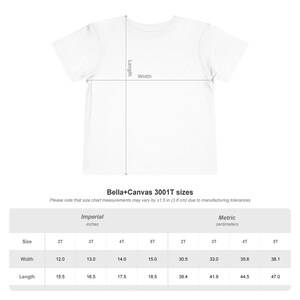 Peut inclure: Un t-shirt blanc avec un diagramme indiquant les mesures de longueur et de largeur. Sous le t-shirt se trouve un tableau des tailles Bella+Canvas 3001T avec les tailles 2T, 3T, 4T et 5T, indiquant la largeur et la longueur en cm.