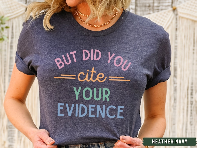Op de afbeelding: Een heideblauw t-shirt met de tekst "But did you cite your evidence" in kleurrijke letters.