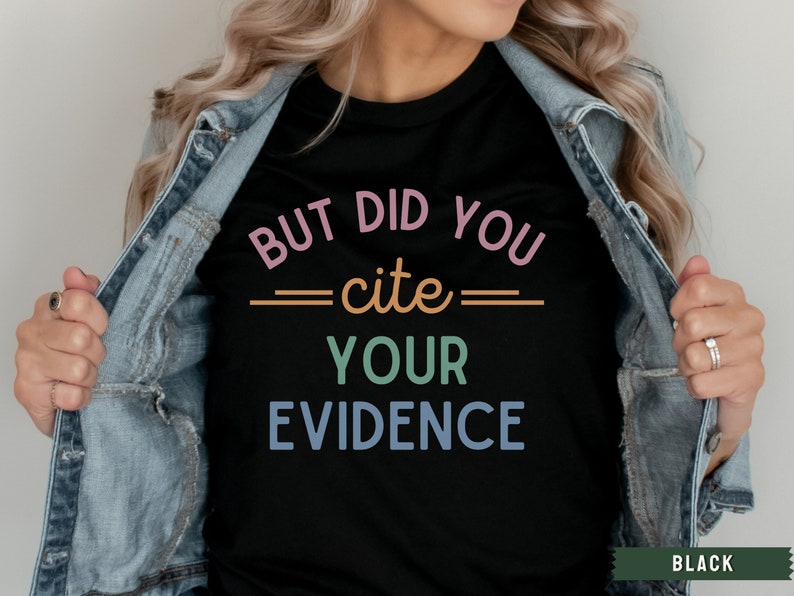 Op de afbeelding: Een zwart T-shirt met de tekst "BUT DID YOU =cite= YOUR EVIDENCE" in kleurrijke letters.