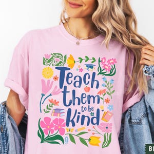 May include: Pink t-shirt with a floral design and the text "Teach them to be kind".
