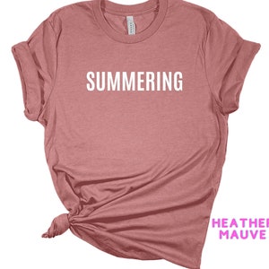 May include: A heather mauve t-shirt with the word "SUMMERING" printed in white on the front.