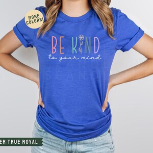 May include: A royal blue t-shirt with the text "BE KIND to your mind" in rainbow colors. The text is surrounded by a flower graphic.