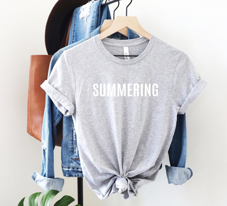 May include: Gray t-shirt with the word "SUMMERING" printed in white on the front.