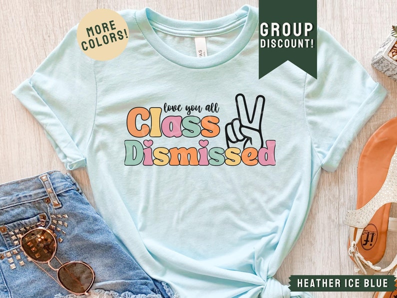 May include: A light blue t-shirt with the text "love you all Class Dismissed" in colorful letters with a peace sign. The text is in a retro font style.