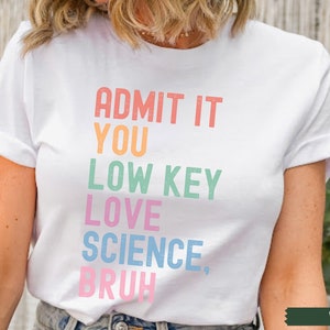 May include: White t-shirt with the text "ADMIT IT YOU LOW KEY LOVE SCIENCE, BRUH" in rainbow colors.