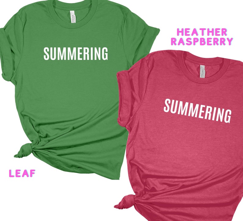 May include: Two t-shirts with the word "SUMMERING" printed in white on the front. The shirt on the left is green and the shirt on the right is a heather raspberry color.