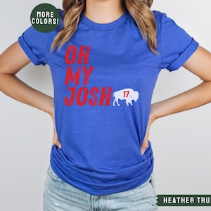 May include: A royal blue t-shirt with the text "Oh My Josh" in red and a white buffalo with the number 17 on it.