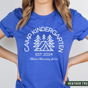 May include: A royal blue t-shirt with a white graphic of a camping scene with the text "Camp Kindergarten Est. 2024 Hillview Elementary School".