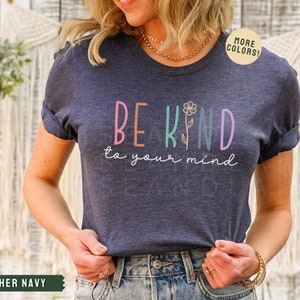 May include: A heather navy blue t-shirt with the text "Be Kind to your mind" in colorful letters with a small flower graphic.