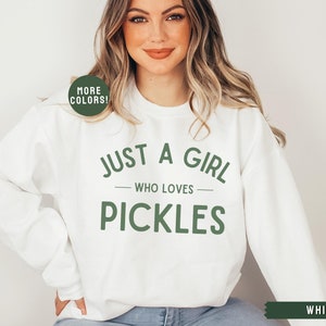 May include: White sweatshirt with the text "Just a girl who loves pickles" in green lettering.