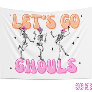 May include: White tapestry with the text "Let's Go Ghouls" in pink and orange bubble letters. Three skeletons wearing cowboy hats are dancing in front of the text. The tapestry is 36 inches by 26 inches.