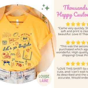 May include: Yellow V-neck t-shirt with a graphic design featuring football-themed illustrations and the text "Let's go Buffalo." The design includes a football, a helmet, and the number 50. The shirt is hanging on a wooden hanger.