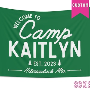May include: A green fabric banner with white text that reads "Welcome to Camp Kaitlyn Est. 2023 Adirondack Mts." The banner is 36 inches by 26 inches.