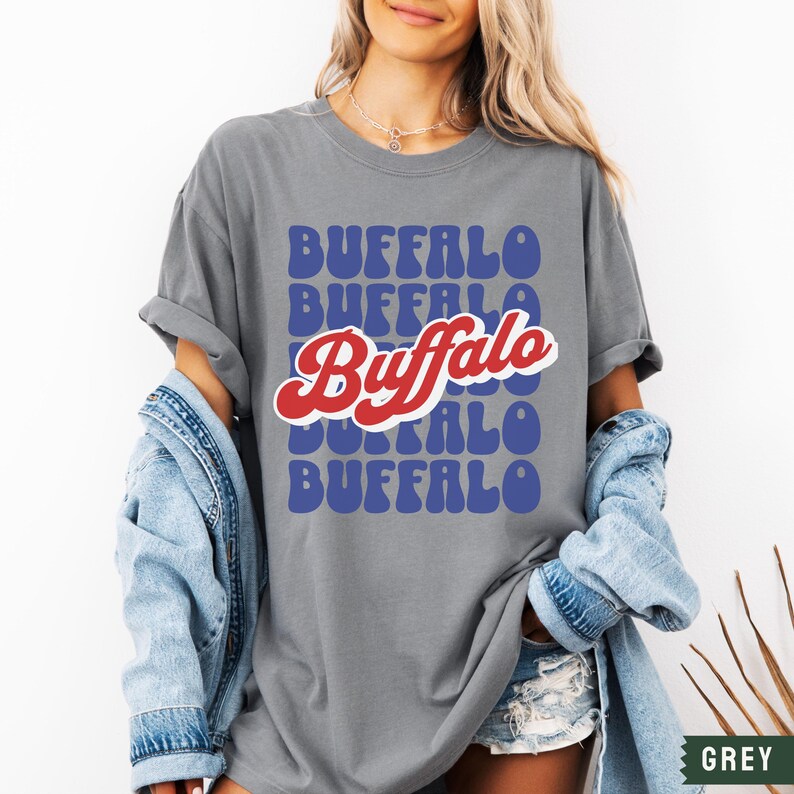 May include: A grey t-shirt with a retro-style graphic design featuring the word "Buffalo" repeated in blue and red letters.
