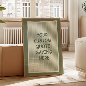 Peut inclure: Une affiche encadrée avec le texte "YOUR CUSTOM QUOTE SAYING HERE" dans un motif à rayures vertes et blanches. L'affiche est dans un cadre en bois et est appuyée contre une boîte en carton. L'arrière-plan comprend une fenêtre et une plante.