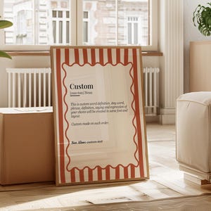 Könnte beinhalten: Ein gerahmter Druck mit der Definition des Wortes "Custom". Der Druck hat einen cremefarbenen Hintergrund mit einem rot-weiß gestreiften Rand. Der Text lautet "Custom" und liefert eine Definition. Der Druck wird in einem hellen Raum angezeigt.