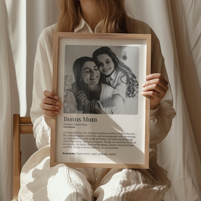 May include: A black and white photo of a woman and a girl hugging. The photo is in a wooden frame with a white background. The text below the photo reads "Bonus Mom [Mother's Name] Noun A loving individual who chooses to embrace another's child as her own. She provides support, protection, and encouragement with unwavering care and affection. A role model and friend, she builds bonds through shared experiences and mutual respect. Though not connected by blood, she enriches the family, showing that being a parent is about the heart, not DNA. Deeply loved and admired, she is a true hero. Synonyms: Superwoman, angel, protector, warrior"