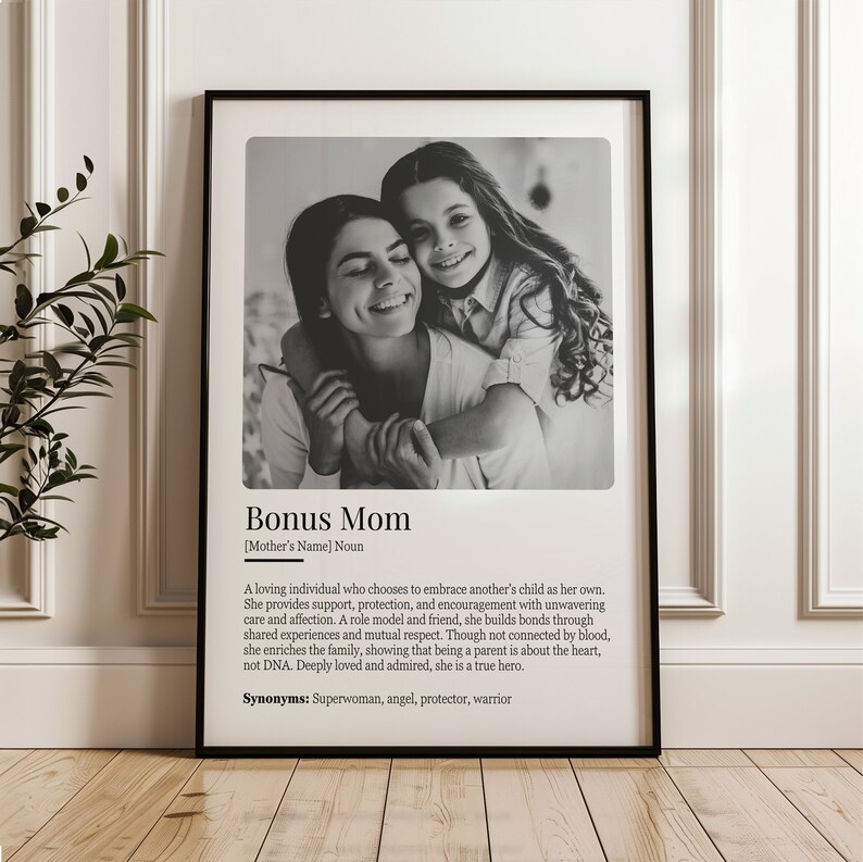 May include: Black and white photo of a woman and a girl hugging. The photo is framed and has a definition of "Bonus Mom" with the text "A loving individual who chooses to embrace another's child as her own. She provides support, protection, and encouragement with unwavering care and affection. A role model and friend, she builds bonds through shared experiences and mutual respect. Though not connected by blood, she enriches the family, showing that being a parent is about the heart, not DNA. Deeply loved and admired, she is a true hero. Synonyms: Superwoman, angel, protector, warrior"