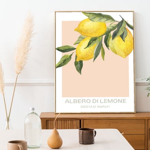 Op de afbeelding: Een aquarel schilderij van een tak van een citroenboom met drie citroenen. De achtergrond is perzikkleurig met de tekst "ALBERO DI LIMONE COSTA D'AMALFI" in zwart.