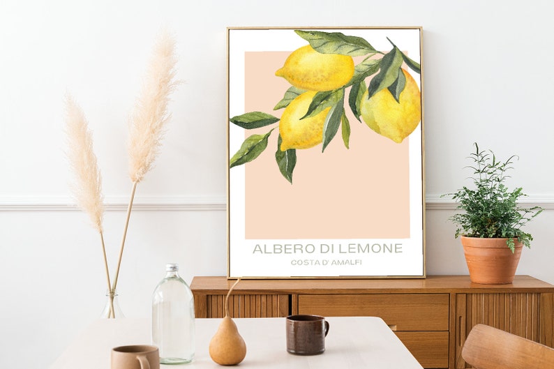 Op de afbeelding: Een aquarel schilderij van een tak van een citroenboom met drie citroenen. De achtergrond is perzikkleurig met de tekst "ALBERO DI LIMONE COSTA D'AMALFI" in zwart.