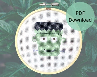 Puede incluir: Un patrón de punto de cruz de un monstruo de Frankenstein verde con pelo negro, ojos marrones y una cicatriz cosida en la frente. El patrón está en un aro de bordado amarillo. El texto "PDF Download" está en un círculo verde.