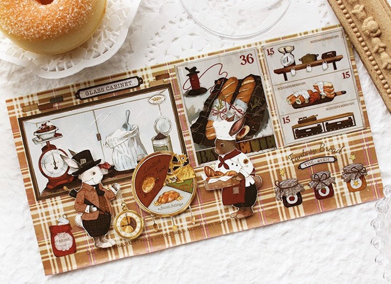Op de afbeelding: Een verzameling vintage-stijl bakkerstickers met een konijnenbakker, een klok, een weegschaal en potten jam. De stickers zijn gedrukt op een bruin-witte geruite achtergrond met de tekst "Glass Cabinet" en "Fantasy Bread" zichtbaar.