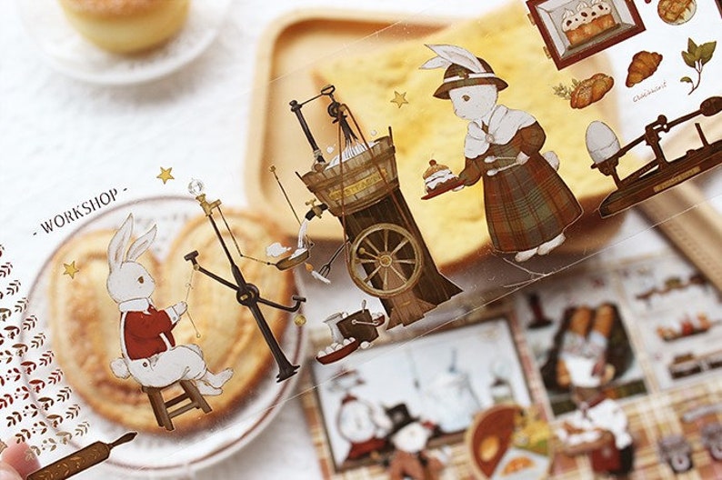 Op de afbeelding: Een vel met transparante stickers met illustraties van konijnen, gebak en vintage bakkerijapparatuur. De stickers zijn bedrukt met de tekst "Workshop -" en "Choux a la Creme".