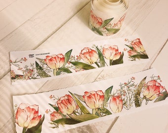 May include: A roll of washi tape with a floral design featuring pink and white tulips and small white flowers. The tape is on a wooden surface.