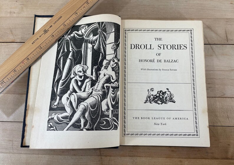 May include: An open book titled "The Droll Stories of Honor&eacute; de Balzac" with illustrations. The book has a black and white illustration on the left page and text on the right. A wooden ruler rests on the book.