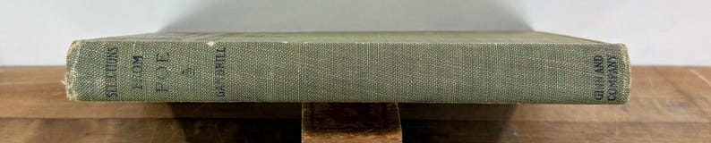 K&ouml;nnte beinhalten: Ein salbeigr&uuml;ner Buchr&uuml;cken mit texturiertem Stoffmaterial. Der Text auf dem Buchr&uuml;cken lautet Selections from Poe, herausgegeben von Gambrill, und Ginn and Company am unteren Rand. Das Buch weist Gebrauchsspuren an den Kanten und Ecken auf.