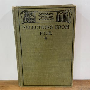 K&ouml;nnte beinhalten: Ein gebundenes Buch mit dem Titel Selections from Poe aus der Reihe Standard English Classics. Der Einband ist olivgr&uuml;n mit schwarzem Text und einem dekorativen Rahmen, der heraldische Symbole und ein kleines Kronensymbol unter dem Titel zeigt.
