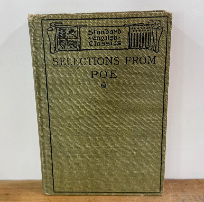 K&ouml;nnte beinhalten: Ein gebundenes Buch mit dem Titel Selections from Poe aus der Reihe Standard English Classics. Der Einband ist olivgr&uuml;n mit schwarzem Text und einem dekorativen Rahmen, der heraldische Symbole und ein kleines Kronensymbol unter dem Titel zeigt.