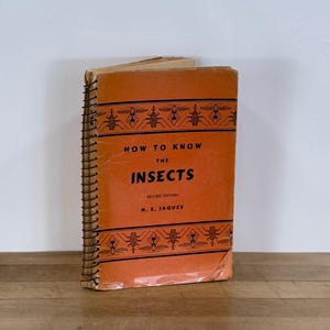 May include: An orange book titled "How to Know the Insects" with black text and insect illustrations. The book is spiral-bound and shows signs of wear. The author's name, H. E. Jaques, is also visible.